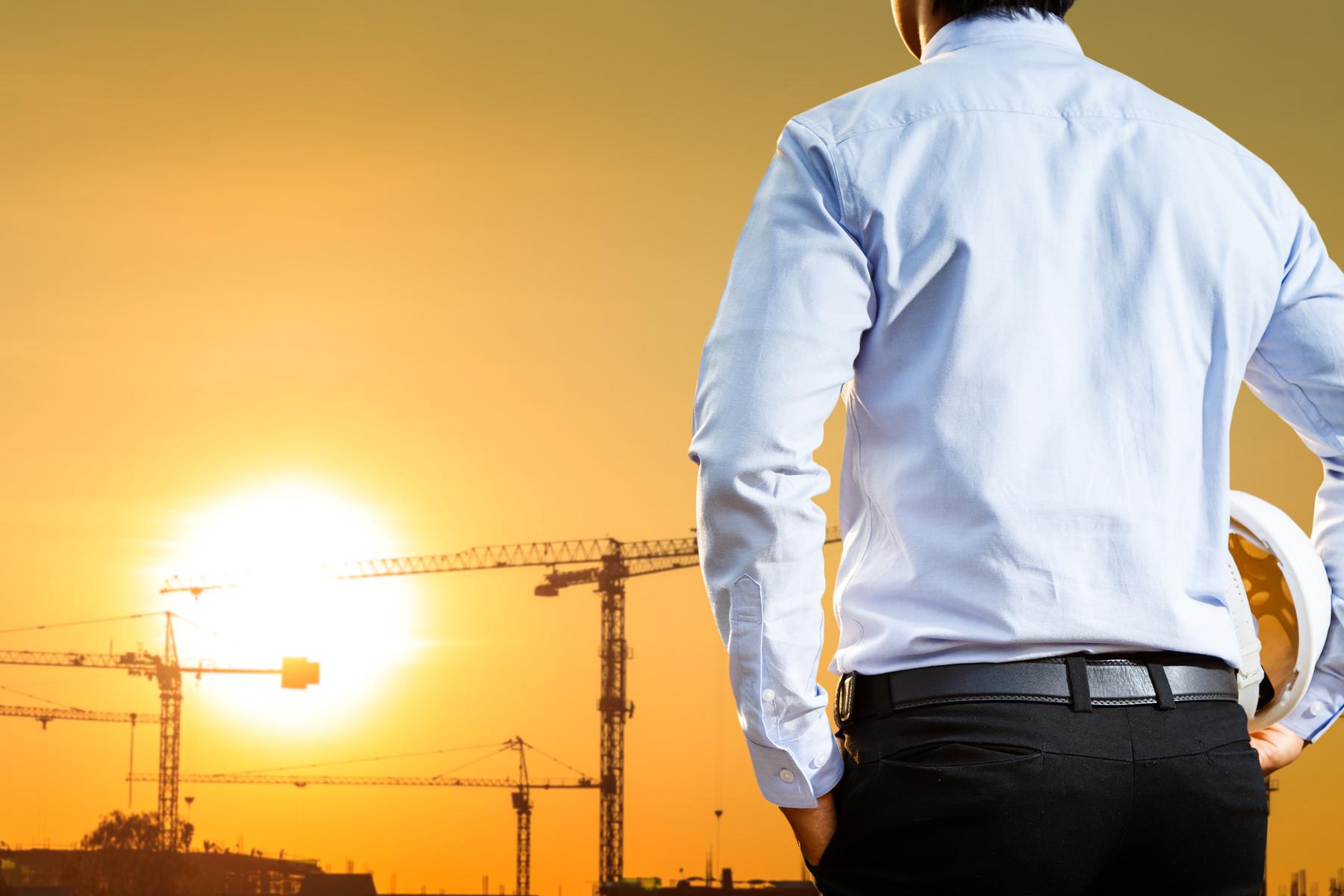 Site professional overlooking cranes at sunset